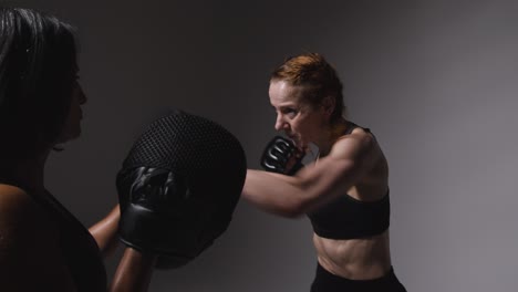 Studio-Shot-Of-Two-Mature-Women-Wearing-Gym-Fitness-Clothing-Exercising-Boxing-And-Sparring-Together-2